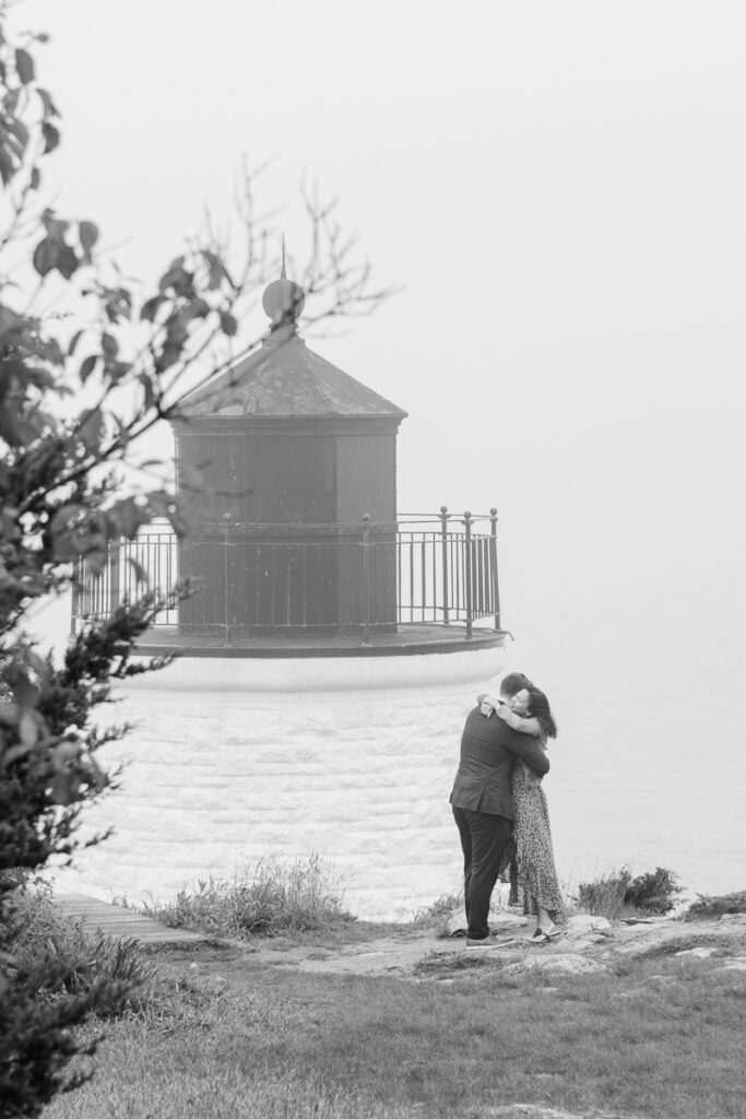 couple hugs after surprise proposal at castle hill inn and lighthouse