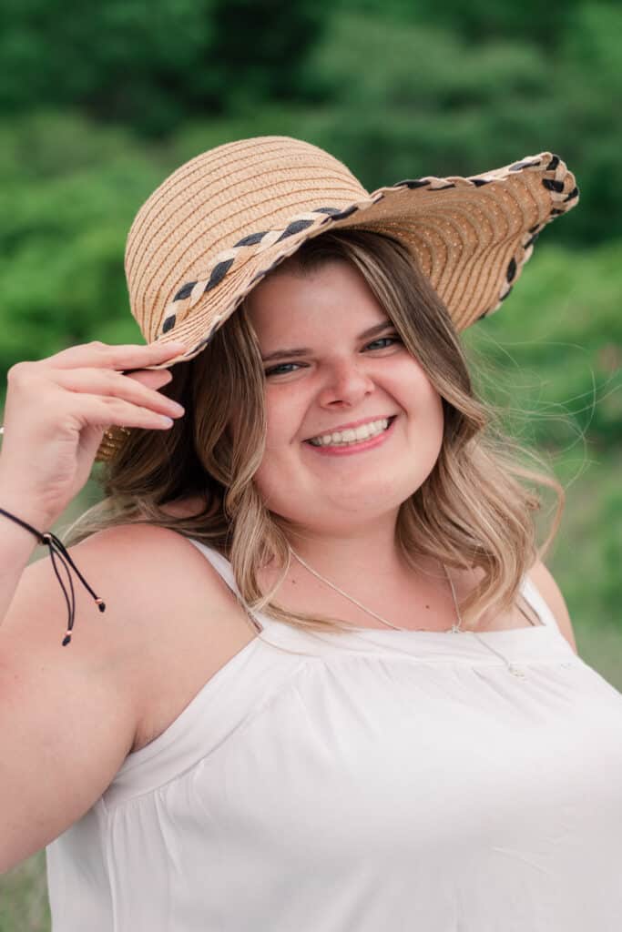 girl poses with hat for beach portraits