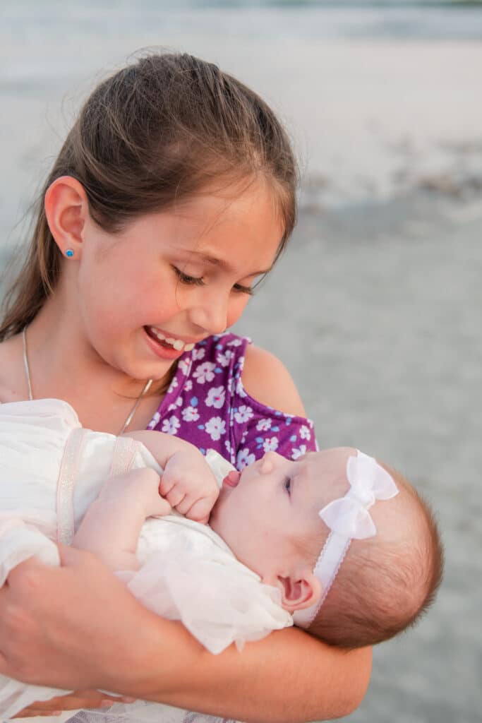 girl holds baby during newborn photography session