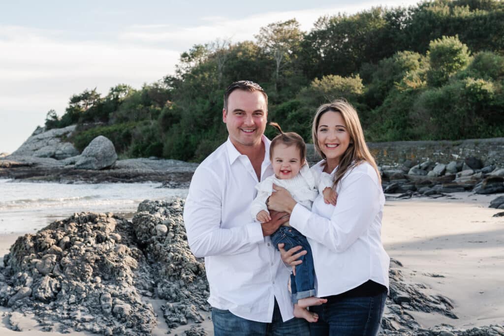 family of three poses on the beach