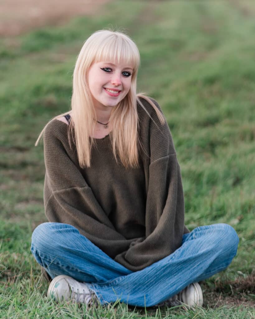 girl sits in grass at glen farm stables